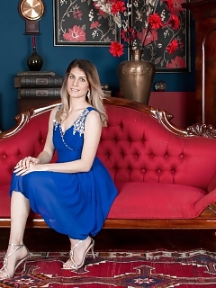 Ashleigh Mckenzie Is Wearing Her Good-looking Blue Gown Along Side Her Red Couch